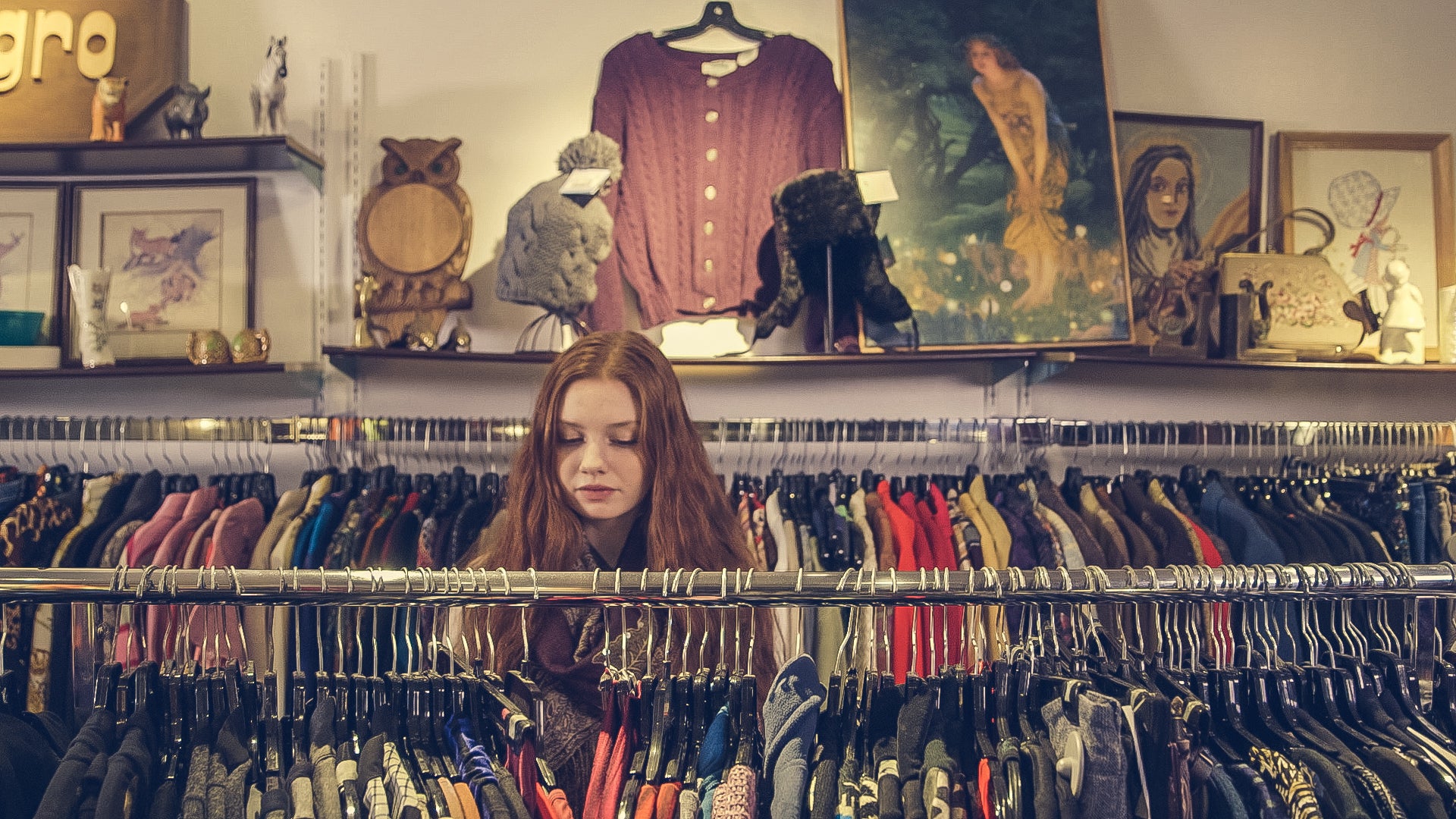 a woman searching through clothing aisle.